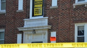 A bright orange signs warns people not to enter the buildings.