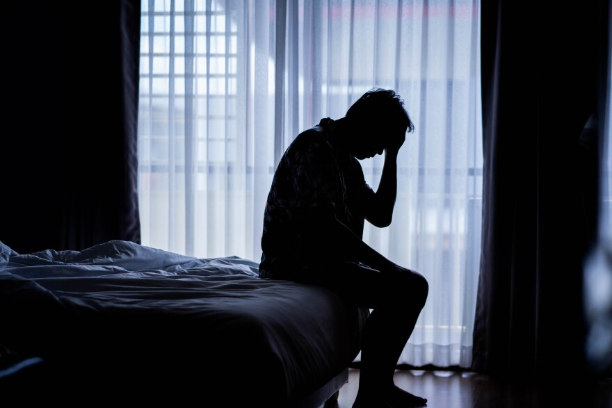 Depressed man sitting on a bed