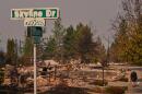 A street sign shows sign of fire damage as a person walks their dog after a wildfire hit the northern part of Spokane, Wash., Monday, Aug. 3, 2026. (Lindsey Wasson/AP)