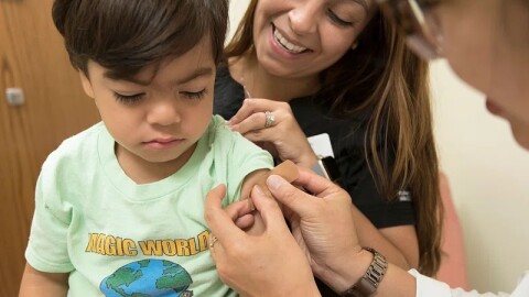 A doctor places a bandage on the injection site of a child. 