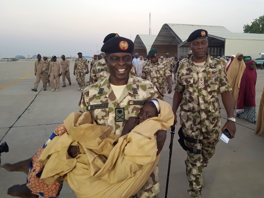 Maj. Gen. Rogers Nicholas, Theatre Commander, carries one of the freed students during a handover to government officials in Maiduguri on Wednesday.