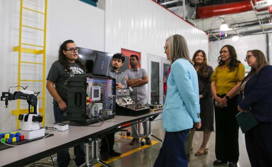 Jose Zapata discusses technical training equipment with Hobbs and other visitors.