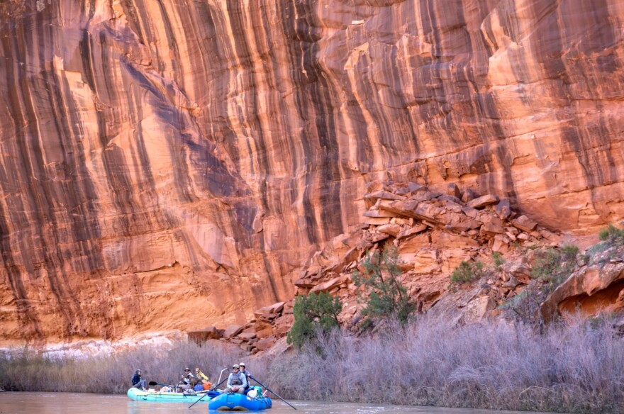 Boaters float past ancient sandstone cliffs formed in the Jurassic Era inside Dolores River Canyon, Apr. 23, 2023, near Bedrock.