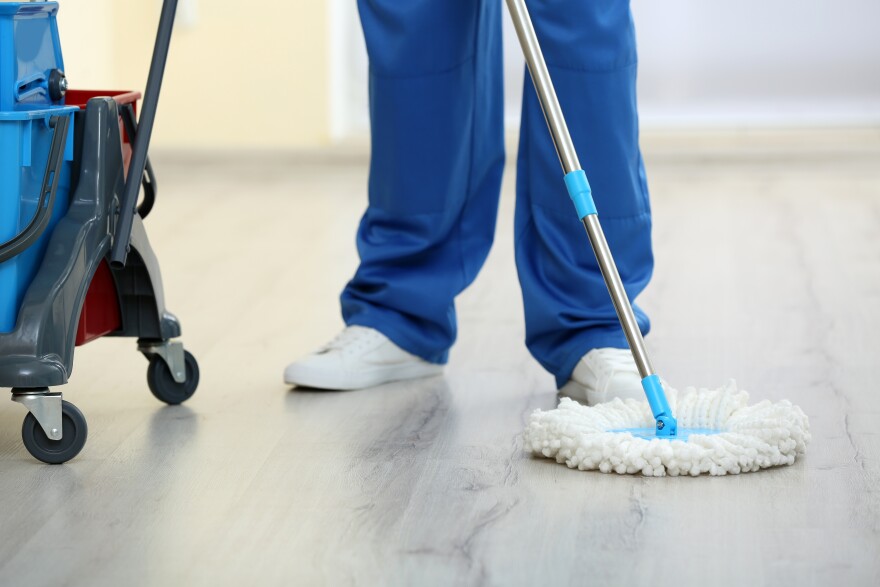 Young man with mop cleaning floor in the room, closeup