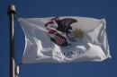 The current state flag depicts the Illinois seal — an eagle standing on a shield with the sun rising on the horizon. A rock under the eagle denotes two years: 1818 and 1868, the year Illinois became a state and the year the state seal was adopted.