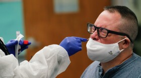 A male teacher squints while receiving a nasal swab COVID-19 test.