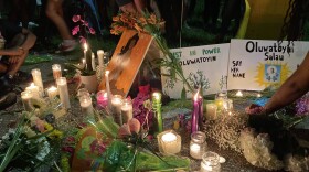 Friends place candles, flowers, and signs down in honor of Oluwatoyin Salau, a 19-year-old woman found dead in Tallahassee, Fl.