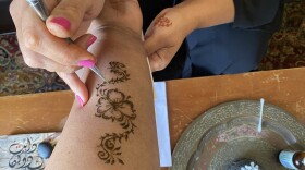Renda Dabit creating a henna design on the arm of Crosscurrents host, Hana Baba.