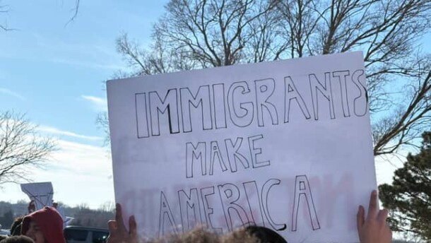 A student holds up a sign that says "Immigrants Make America" during a walkout protest against ICE in Derby.