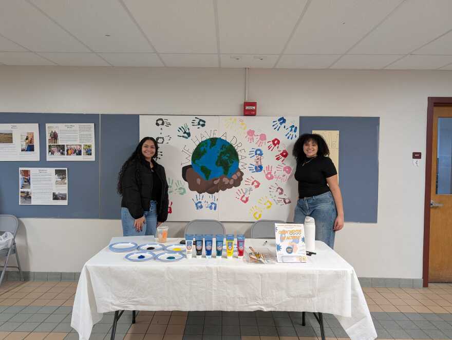 Isabella Gomez (L) and Ayvah Collier (R) stand in front of a mural that attendees of the 44th Annual Martin Luther King, Jr. Day Community Celebration could partipate in by adding their prints of their hands to piece. Gomez and Collier are part of the Manchester Memorial High School student club, Open Minds in Action.