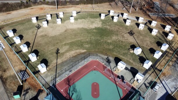 An aerial view of twenty-nine, 2-person pallet shelters in a baseball park.