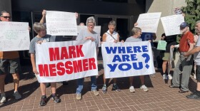 Members of Indivisible Evansville gather in front of the Fifth Third Bank building, home of Rep. Mark Messmer's (R) Evansville office
