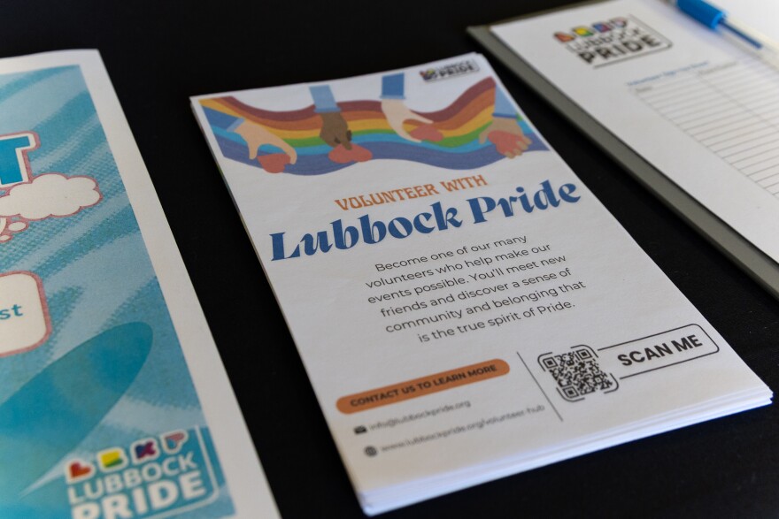 A photo of various pamphlets and sign-ups on the LubbockPRIDE table at the resource fair. Centered is a handout that says 'Volunteer with Lubbock Pride: Become one of our many volunteers who help make our events possible. You'll meet new friends and discover a sense of community and belonging that is the true spirit of Pride.