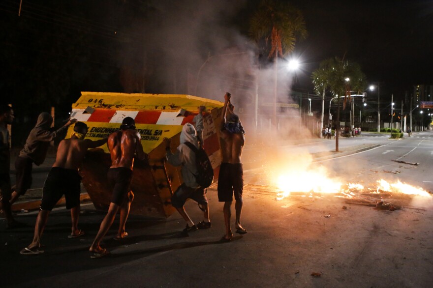 Young men tip a dumpster to make a barricade on Tuesday in Vitoria, Espirito Santo state, Brazil.