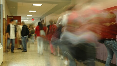 School hallway showing students walking through in a blur.