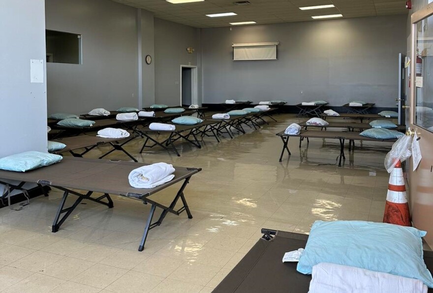 Many cots with pillows and blankets are situated in a room. It's a setup for unhoused residents who need shelter during extremely cold weather.