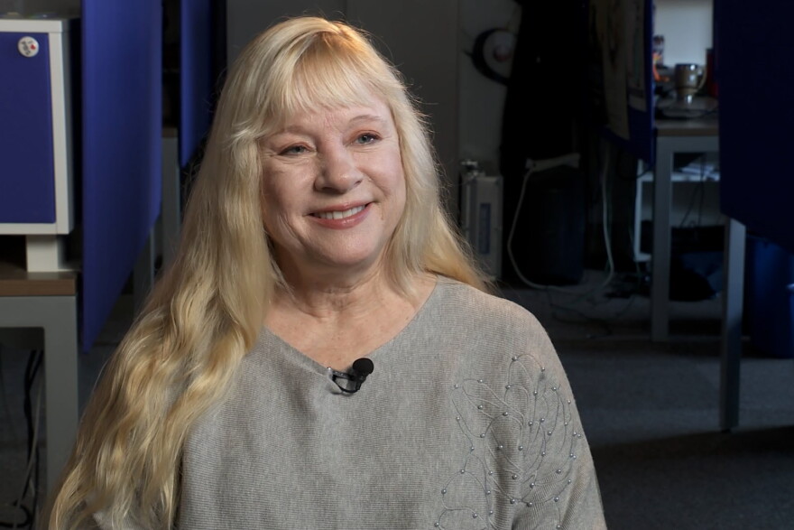 A blonde woman sits in a room.