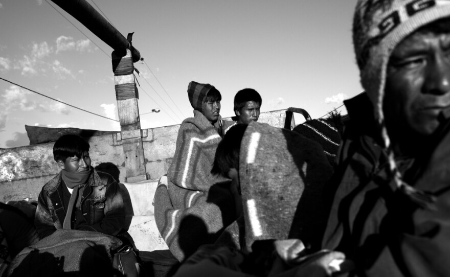 Teenage brothers Fredy and Saman Mamani (center) huddle together to stay warm as they travel atop a gas truck from the Andean crossroads town of Urcos, down into the Amazon Basin where they work in an informal gold mining camp.