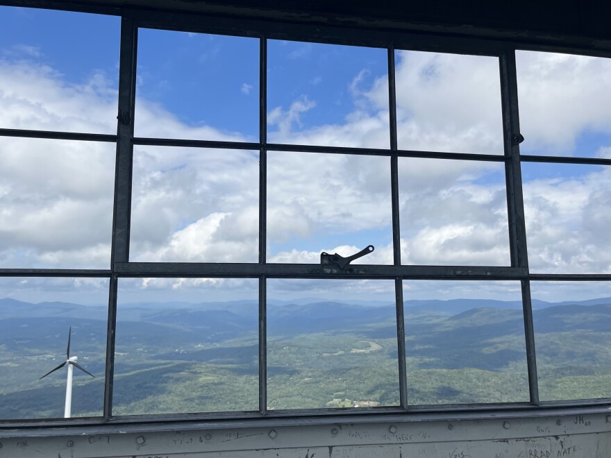 A view of a green and mountainous landscape outside a window with metal panes