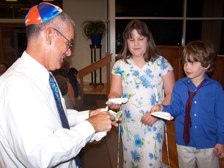 Rabbi Michael Joseph, left, engages with two children during a Passover celebration at Temple Shir Shalom. (Courtesy of Temple Shir Shalom)