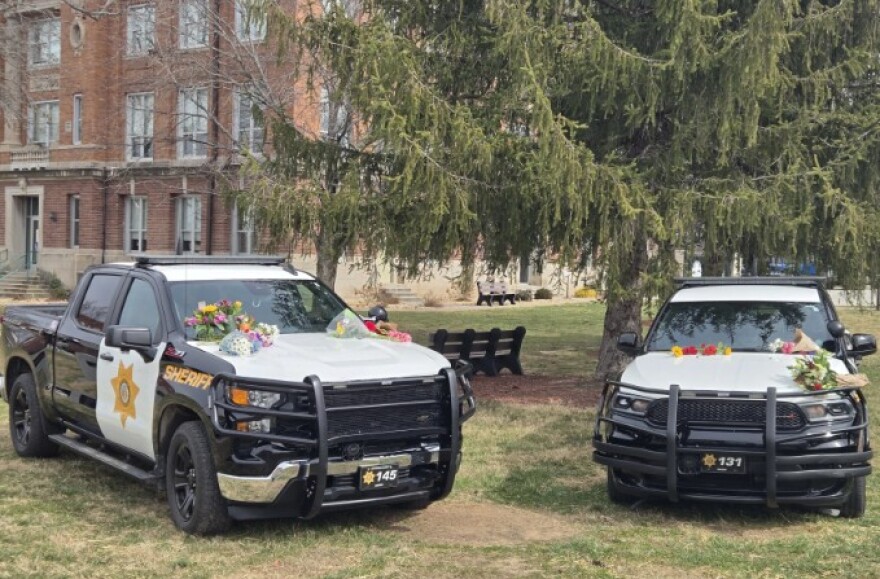 Two Christian County Sheriff's Office vehicles topped with flowers served as a memorial on the Ozark, Mo. square on February 24, 2025.