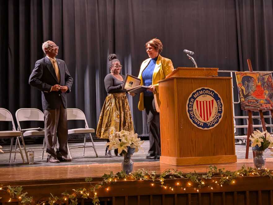 Melanie Levesque, New Hampshire’s first Black state senator, was given the 2026 Martin Luther King Jr. Award at the Martin Luther King Jr. Coalition's 44th annual MLK Day Community Celebration at Manchester Memorial High School. Grace Kindeke, a past recipient and host of the ceremony and James McKim join Levesque on stage.