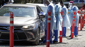 Health workers conduct COVID-19 tests at a drive through coronavirus testing site at a community center. (John Raoux/AP)