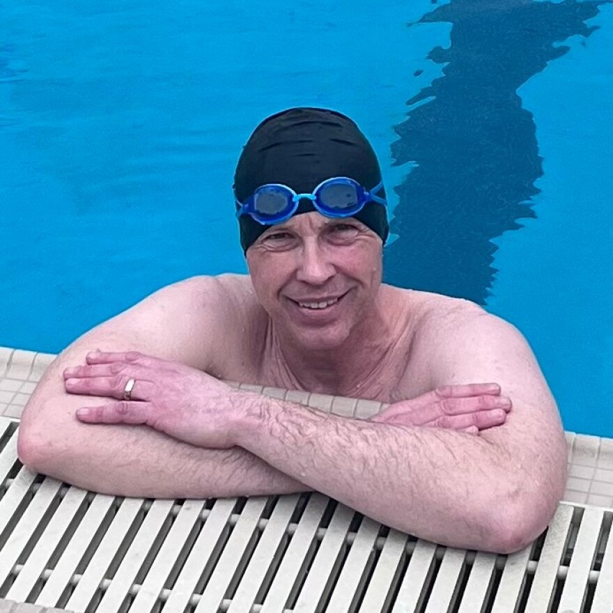 John VanderSloot leaning on the side of a pool in a swim cap