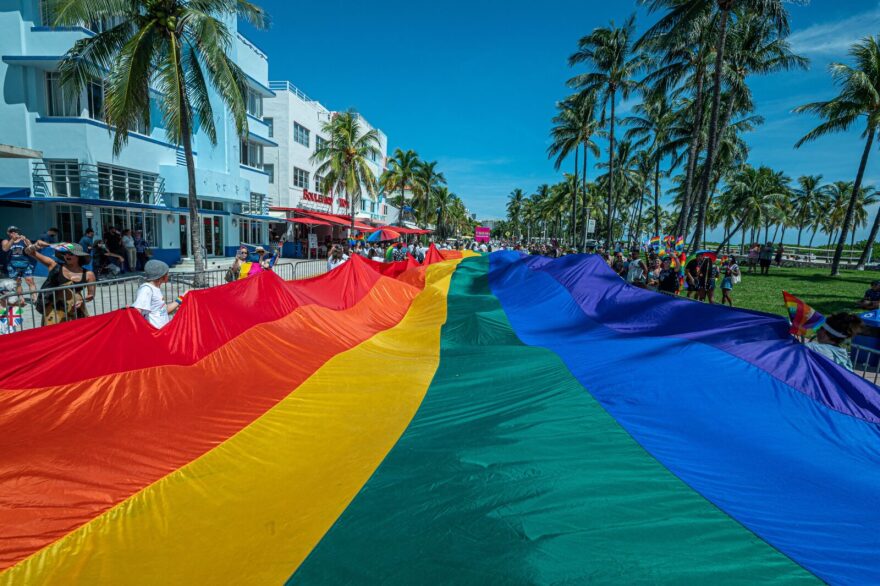 A huge multi-colored flag flies over Ocean Drive as people participate in the Pride Parade, during the Miami Beach Pride Festival, in Lummus Park, South Beach, Florida.