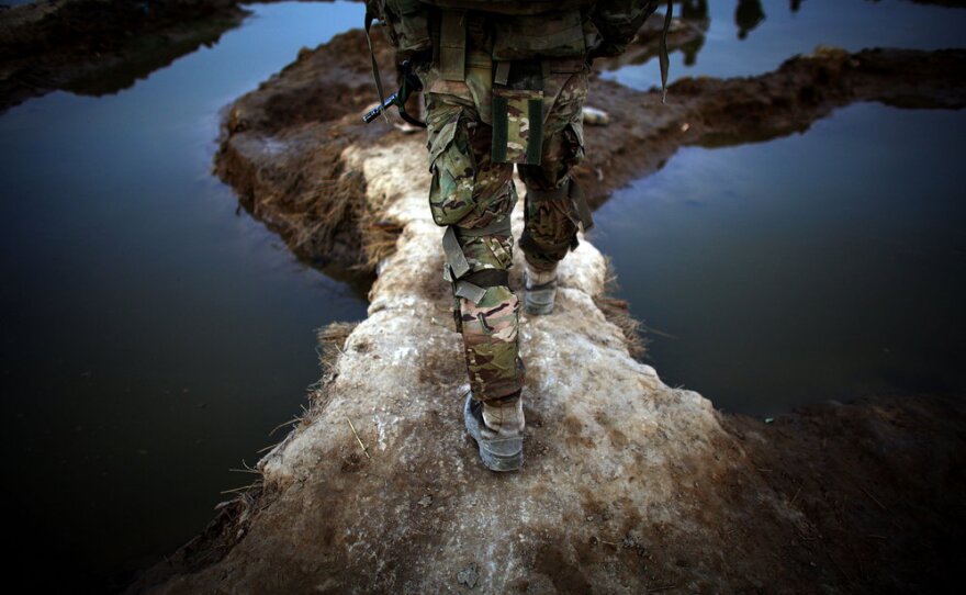 An American soldier walks between puddles while on patrol. U.S. troops based at a combat outpost in the village of Zangabad have nicknamed it "Zangaboom," because roadside bombs are a constant danger.