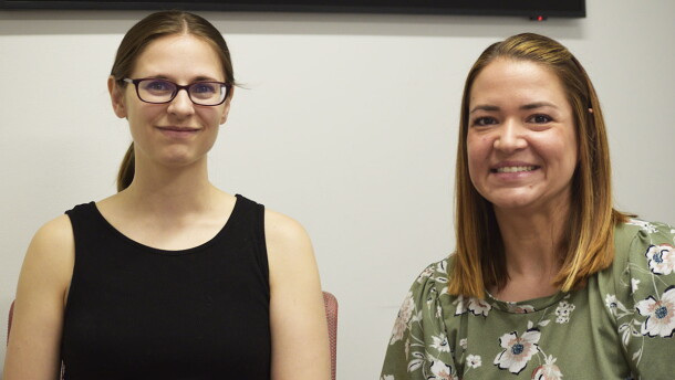 Two women smile for a photo during an interview held in a public radio station studio.  