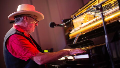 A person plays the piano inside a studio. 