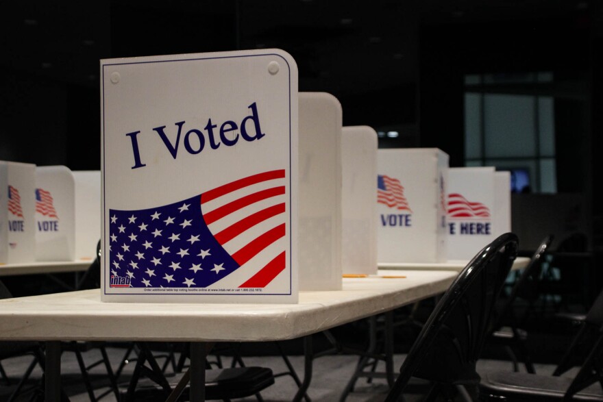 Voting booth dividers sit on white folding tables