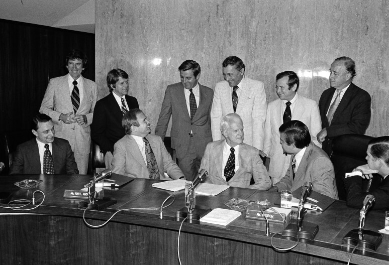 Three counsels to U.S. President Gerald Ford meet with members of the Select Senate Committee on Intelligence in Washington, D.C., June 26, 1975. They brought White House files with them to aid panel's investigation into where orders to assassinate Cuban Premier Fidel Castro originated. From left are: seated, James Wilderoffer, counsel; Roderick Hills, counsel; Philip Buchan, counsel; Sen. Frank Church, D-Idaho, chairman; and Sen. John Tower, R-Texas. Standing, Senators Gary Hartr, D-Colorado; Robert Morgan, D-N.C.; Walter Mondale, D-Minn.; Richard Schweiker, R-Pa.; Howard Baker. R-Tenn.; and Charles McC. Mathias, R-Md.