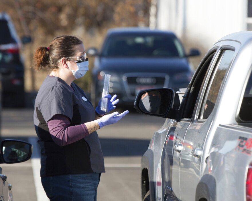 FILE — In this Nov. 24, 2020 file photo an employee gives instructions for self-administering a COVID-19 test in the parking lot at Primary Health Medical Group's clinic in Boise, Idaho. Primary Health Group CEO Dr. David Peterman announced Thursday, July 8, 2021 that all employees of Primary Health will be required to be vaccinated against COVID-19 by September. (AP Photo/Otto Kitsinger, File)