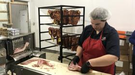 A worker at Swiss Meat and Sausage prepares bacon for sale in 2019.