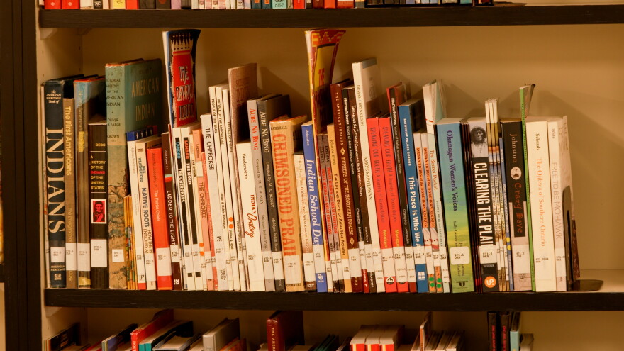A close-up view of a library shelf packed with books on Native American and Indigenous history, including titles like The First Americans and Speaking Our Truth.