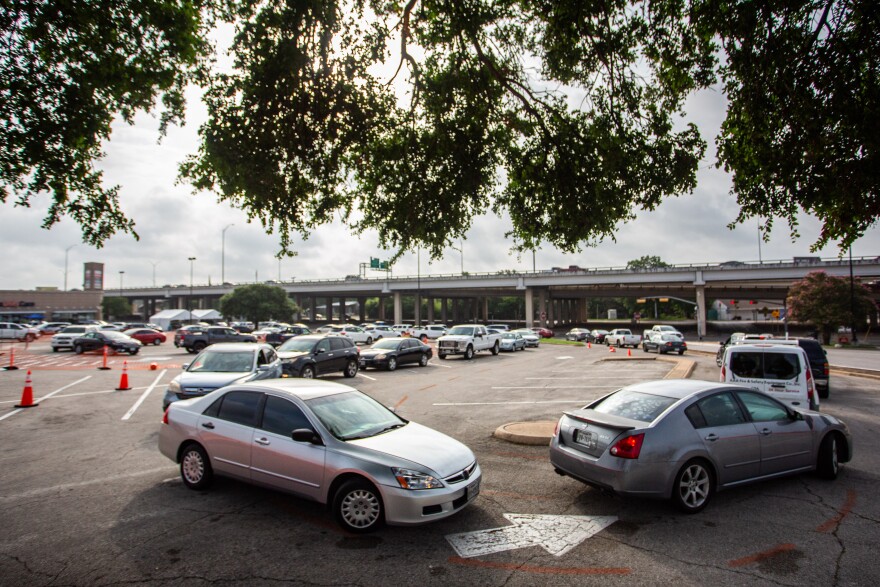 Cars in a CommUnityCare drive-thru testing line snake through the Hancock Center parking lot.