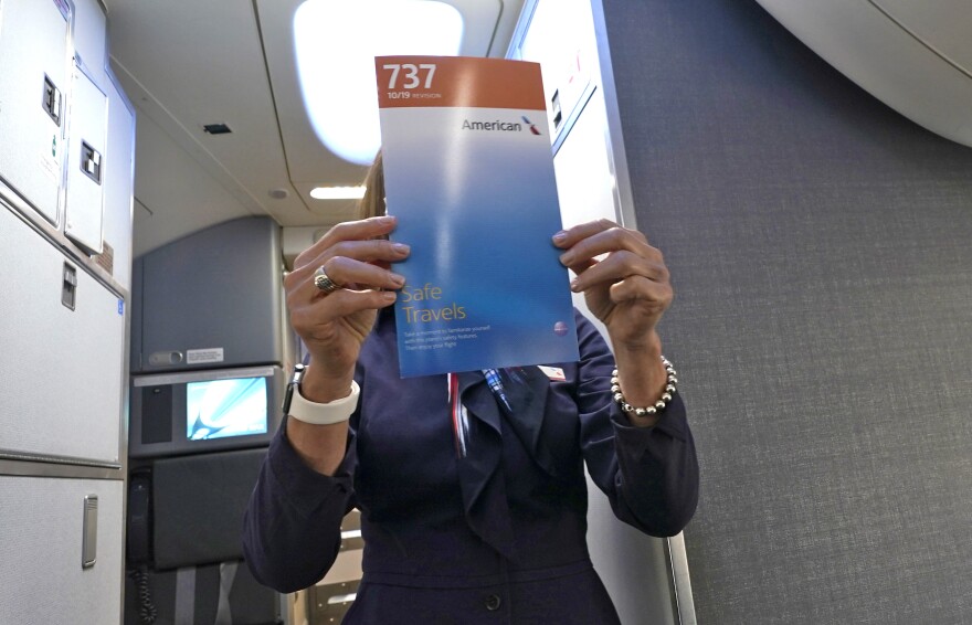 American Airlines flight attendant Pamela Quirin holds up a safety brochure during the preflight safety briefing for passengers aboard a Boeing 737 Max jet departing from Dallas Fort Worth airport in Grapevine, Texas.