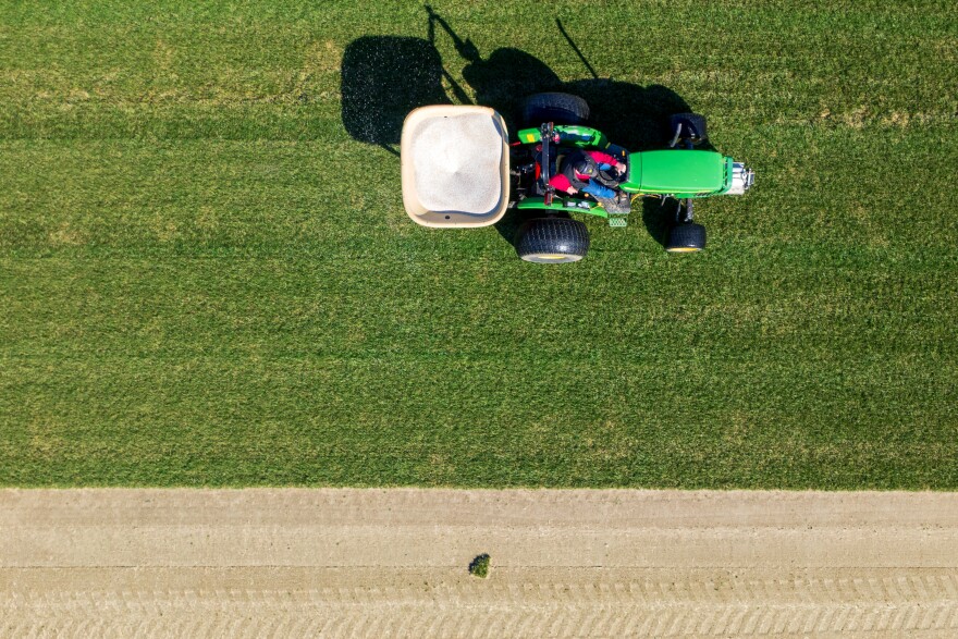 Билл Коллинз разбрасывает удобрения по урожаю дерна в Fairweather Growers. Ферма принадлежала семье Коллинза на протяжении четырех поколений на протяжении более 100 лет. Ферма в Роки-Хилле, штат Коннектикут, выращивает различные сельскохозяйственные культуры на 400 акрах сельскохозяйственных угодий, где, по словам Билла, для работы оборудования фермы требуется около 1500-2000 галлонов топлива в неделю. По словам Коллинза, из-за роста цен на топливо и удобрения из-за войны в Иране они уже решили сократить производство в этом году на 20%, чтобы попытаться сохранить и без того небольшую норму прибыли.