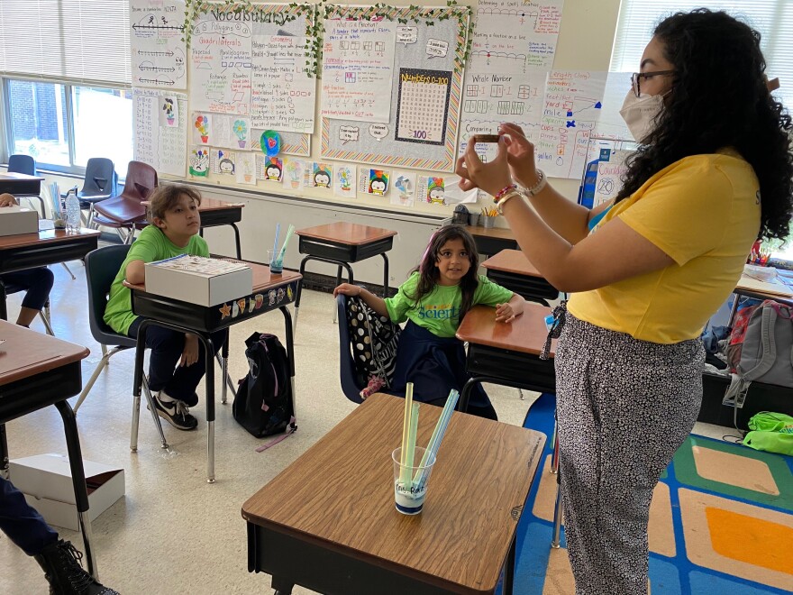  Teacher Zarett Ramirez uses a thin slice of tree branch to demonstrate how rings in trees can be like layers of ice.