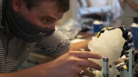 Giant Hailstone on a stand while male scientist examines it. 