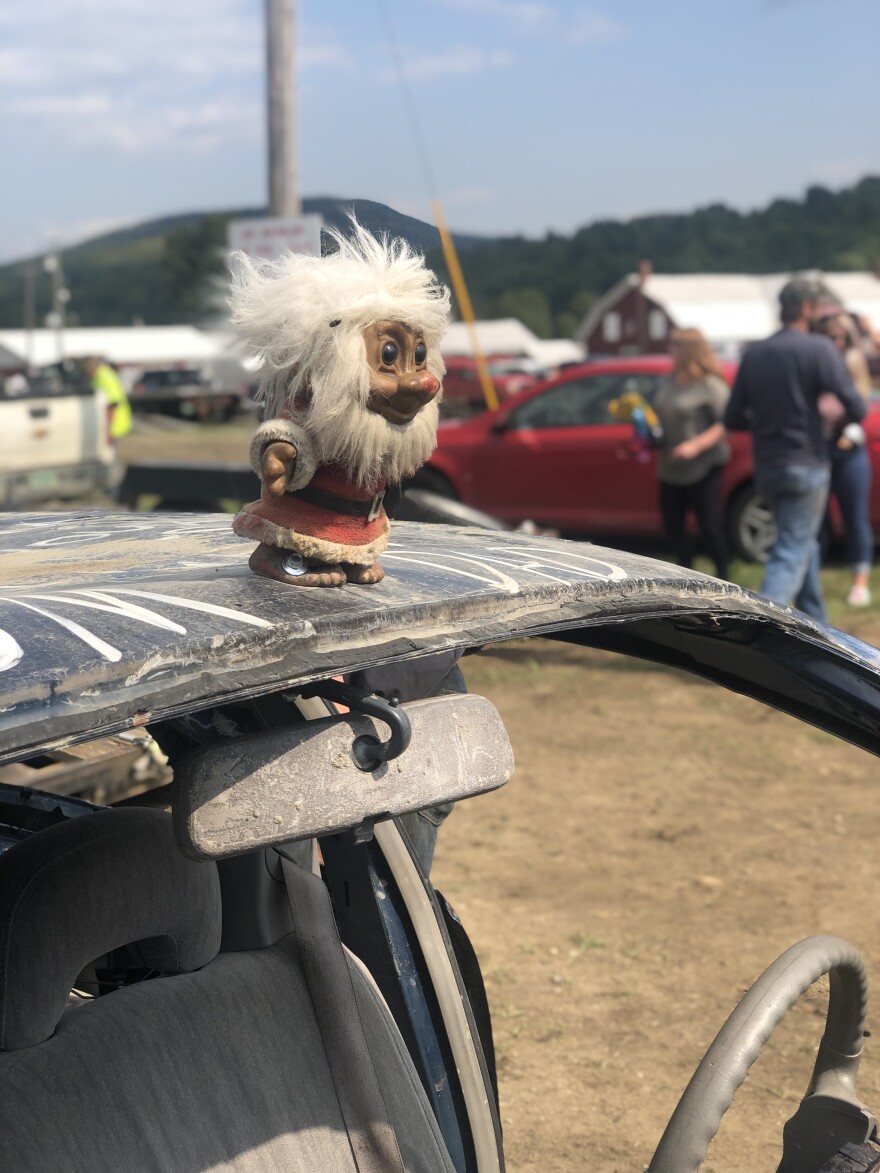 A troll sits on top of a demolition derby car.