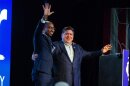 Gov. JB Pritzker, right, is joined by his running mate Christian Mitchell on stage at the Illinois Democratic County Chairs’ Association brunch in Springfield on Aug. 19, 2026.