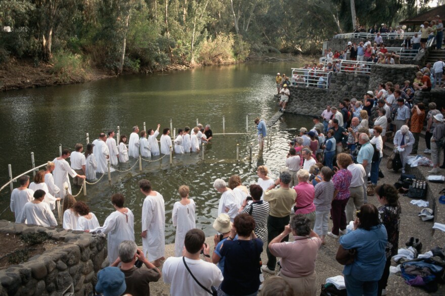 Pilgrims gather on the banks of the Jordan River at Galilee for baptisms. Israeli authorities are eager to accommodate tourists' interest in ancient Israel, according to author Daniel Hummel.