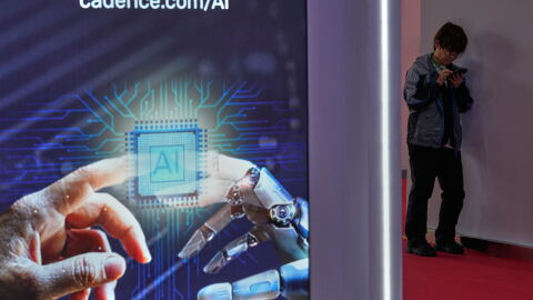 A man browses his phone near an artificial Intelligence (AI) booth at the China International Supply Chain Expo in Beijing on June 25, 2026.