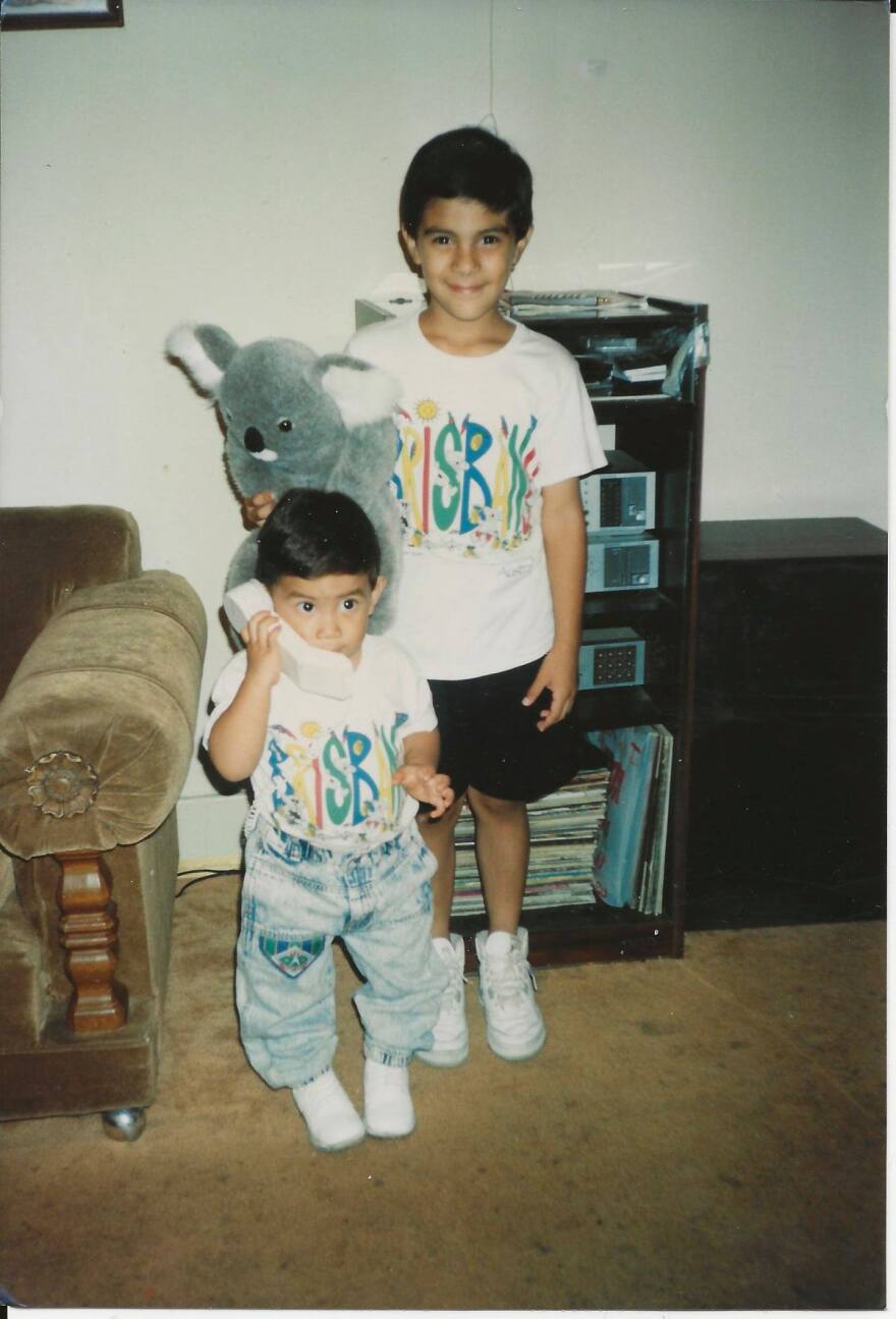 Ricky Hurtado and his bother pictured as kids wearing matching tee shirts and standing in front of a record player counsole.
