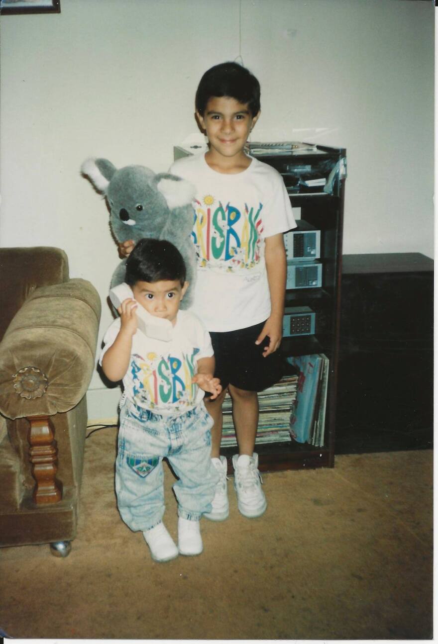 Ricky Hurtado and his bother pictured as kids wearing matching tee shirts and standing in front of a record player counsole. 