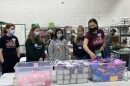 Milwaukee Diaper Mission executive director Meagan Johnson (right) shows local high school students how to package period kits for distribution. About 500 kits were packed during an event for Period Poverty Awareness Week on May 23.