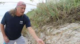Coastal geologist Randall Parkinson points near where Hurricane Dorian sent water inland, eroding dunes that protect coastal infrastructure. Photo by Amy Green